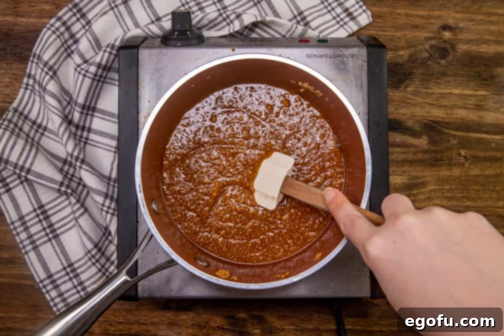 melted butter, brown sugar, milk, sugar, and graham cracker crumbs all melted and stirred together in a pot on an electric stove