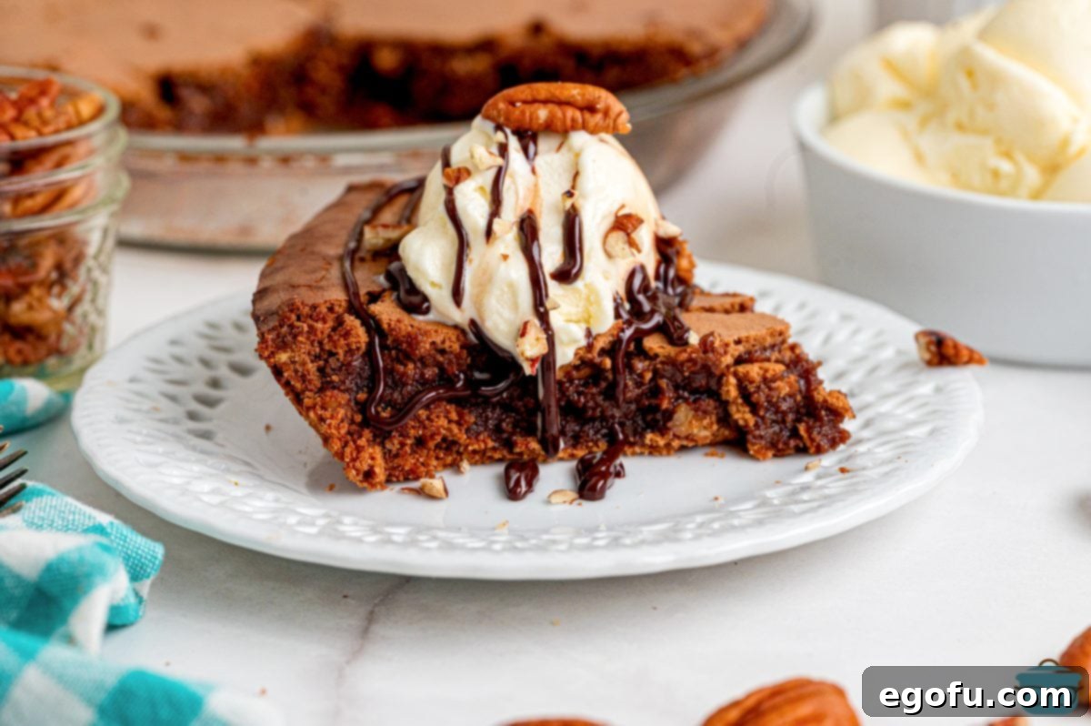 Rich Southern Chocolate Dream 2 A perfectly sliced piece of Southern Fudge Pie, rich and dark, served on a white plate with a scoop of creamy vanilla ice cream and sprinkled with chopped pecans. The pie exhibits its distinct crustless, crispy outer edge.