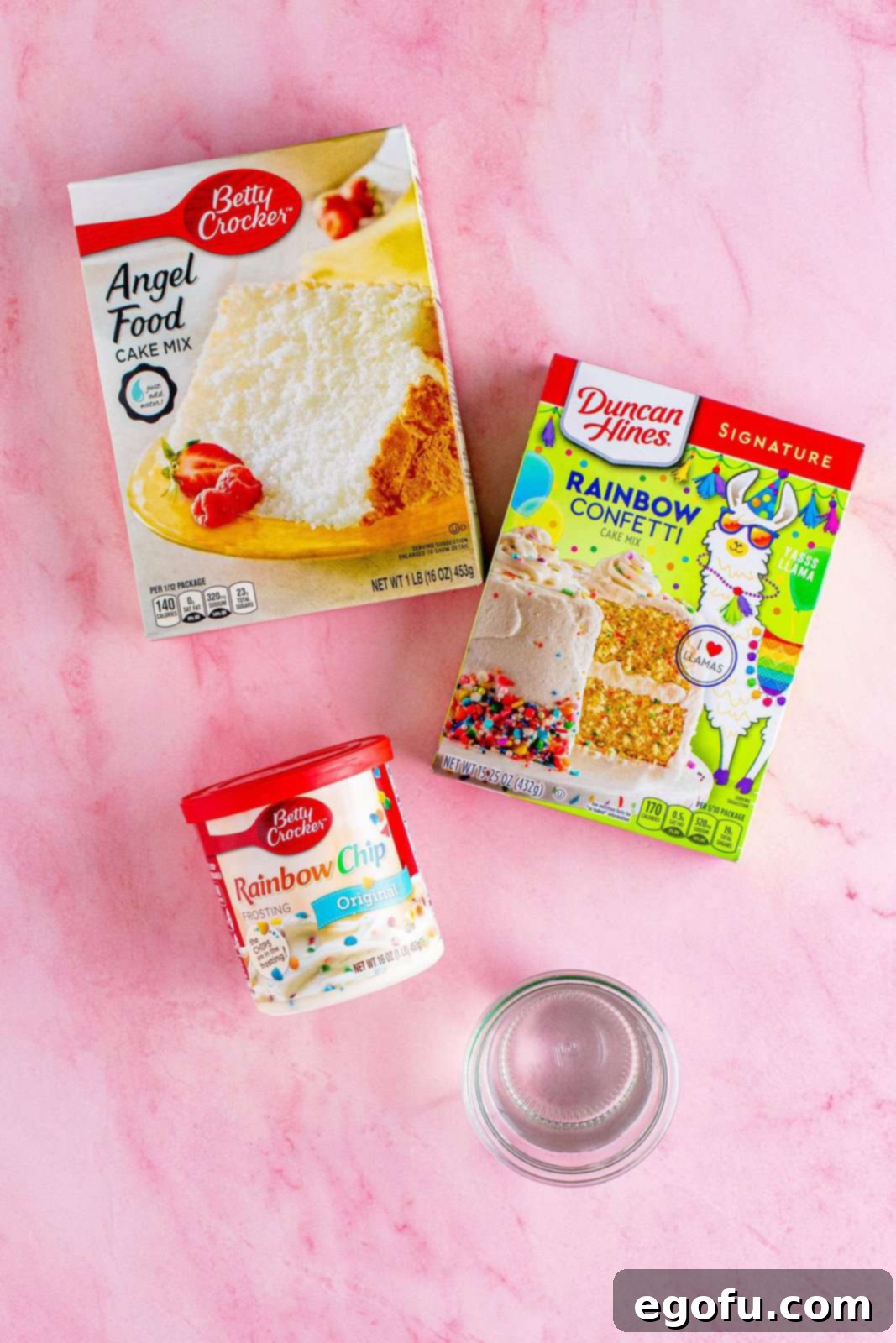 Angel food cake mix, confetti cake mix, and rainbow chip frosting displayed on a countertop.