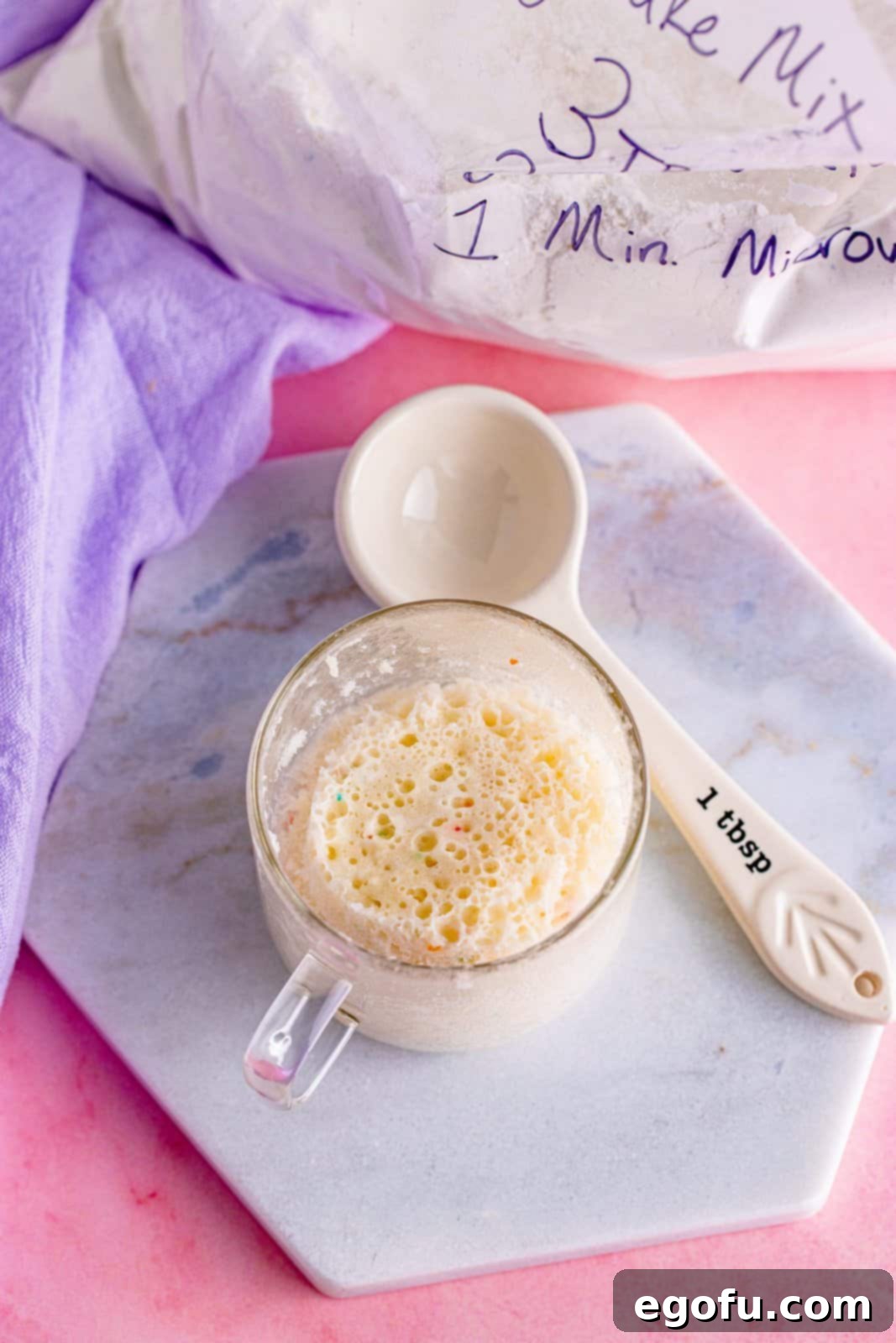 A fully baked and risen mug cake displayed in a clear mug.