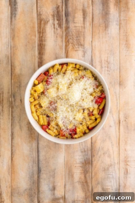 Grated cheese on top of a pasta salad with pepperoni.