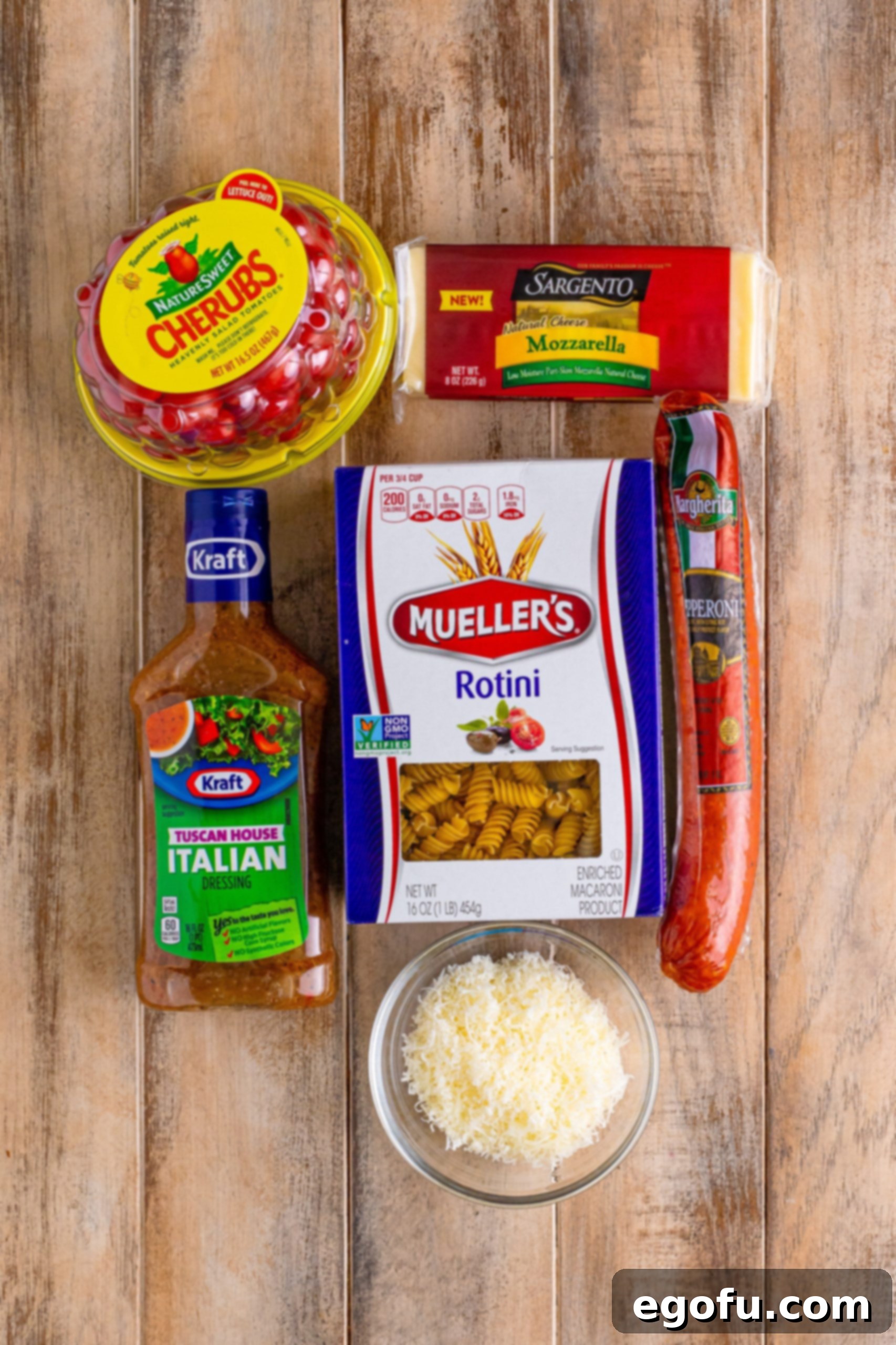 A mozzarella cheese block, cherry tomatoes, Italian dressing, Rotini pasta, and fresh grated parmesan cheese. 