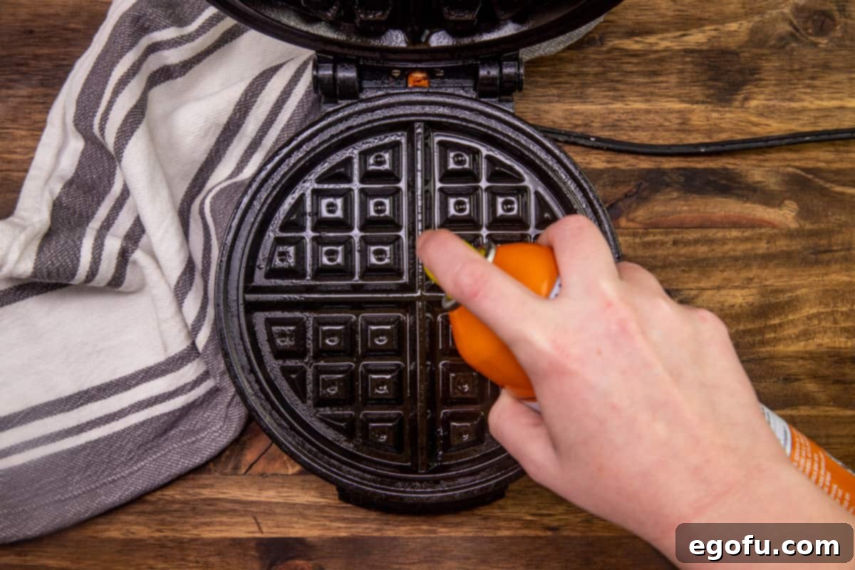 spraying the insides of a waffle maker with nonstick cooking spray.