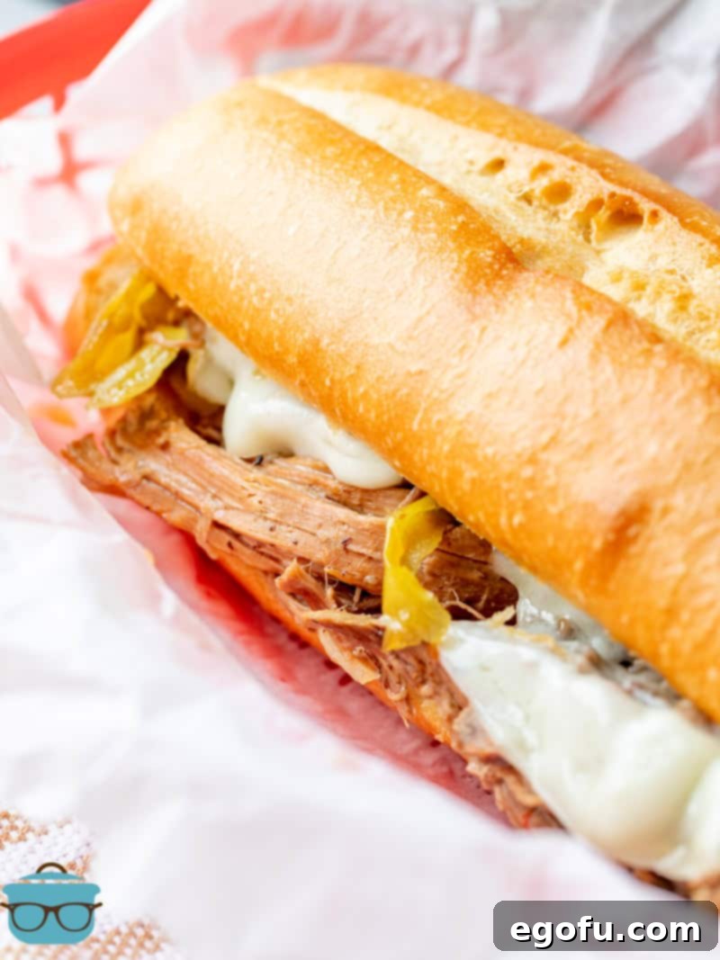 An Italian beef sandwich shown on white parchment paper in a red basket, ready to be enjoyed.