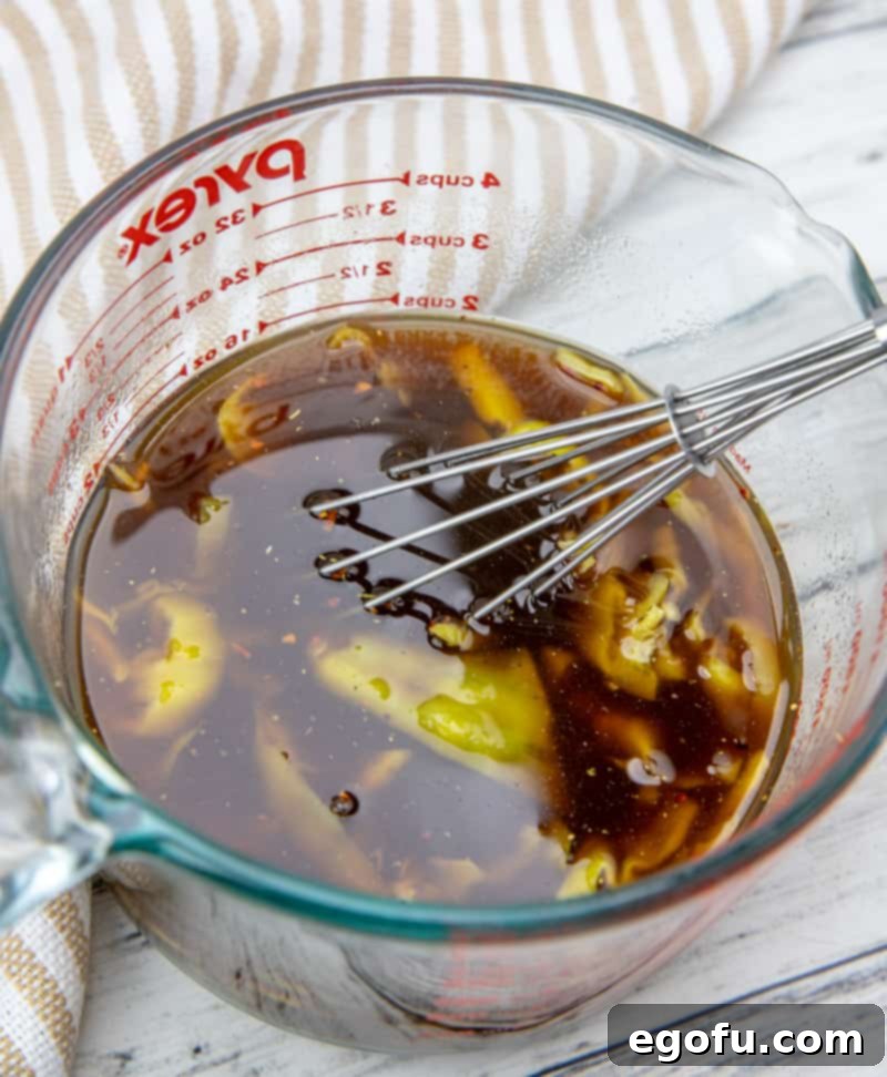 Beef broth, Italian dressing seasoning, and peperoncini with its juices mixed in a bowl.