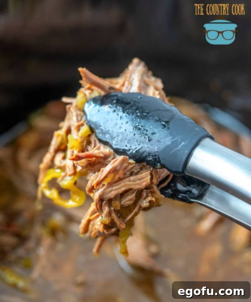 Slow Cooker Italian Beef, rich and saucy, ready to be placed on a sandwich.