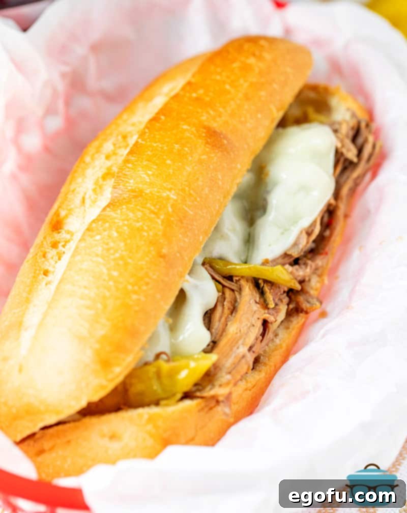 A perfectly assembled Italian Beef Sandwich with melted provolone cheese, served in a basket with parchment paper.