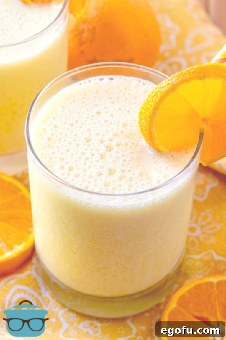 The Best Homemade Orange Julius 7 Copycat Orange Julius Drink in a clear glass with a slice of orange.