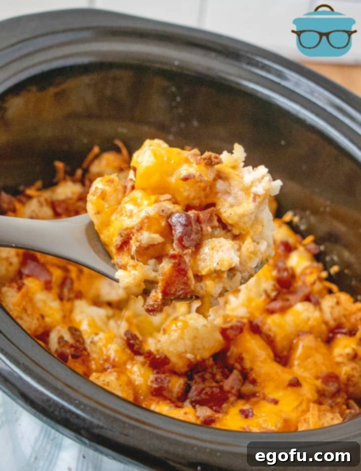 A serving spoon laden with a scoop of the finished Crock Pot Chicken Casserole, showing golden tater tots, melted cheese, and chicken pieces.