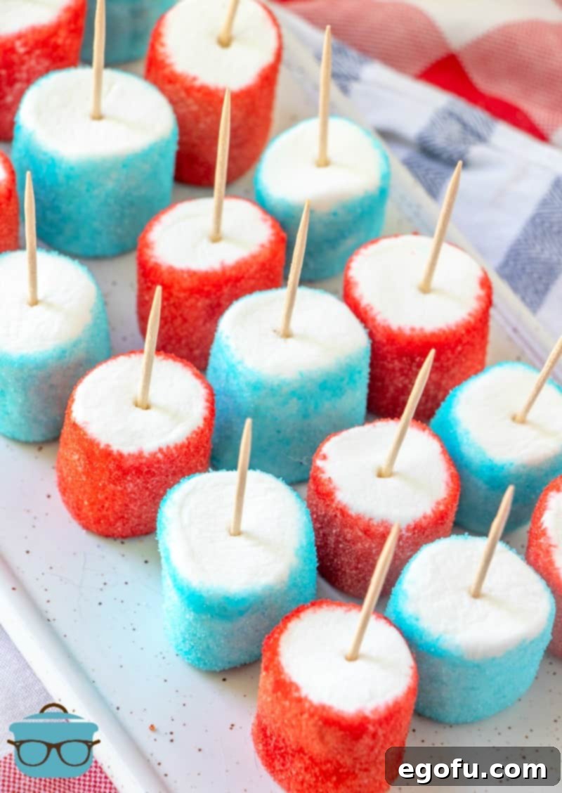 Finished red, white, and blue Jell-O marshmallows with toothpicks, lined up on a white tray after chilling.
