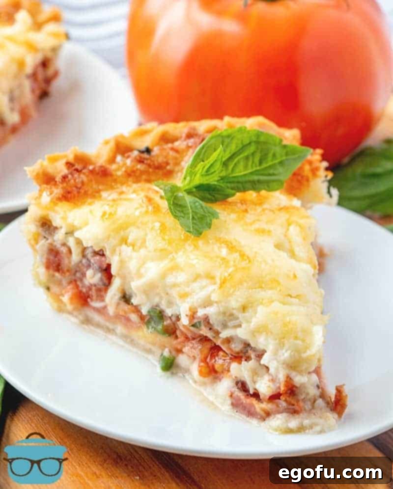 Tomato and Bacon Pie topped with melted mozzarella served on a white plate with a sprig of basil on top