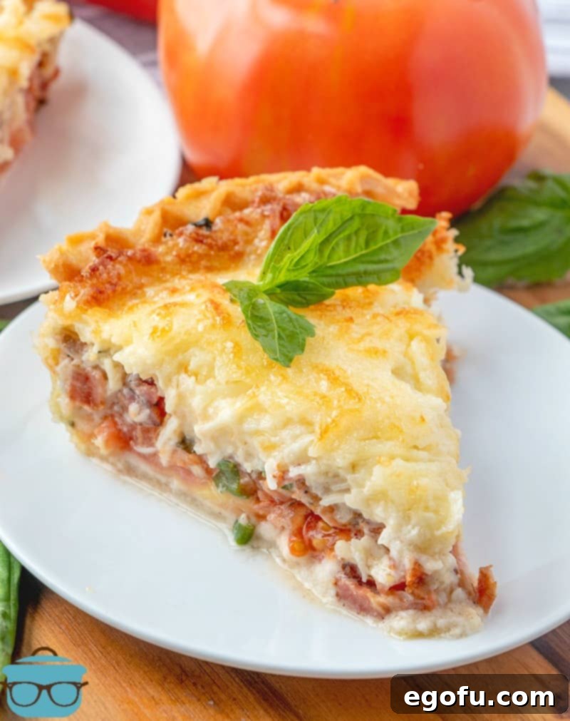 slice of tomato and bacon pie with melted cheese, on a white plate