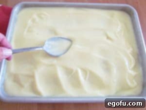 spreading out pudding over cake.