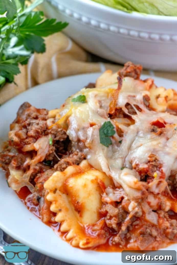 Baked Ravioli Casserole topped with melted cheese and fresh chopped cilantro, served on a small white plate with a side salad.