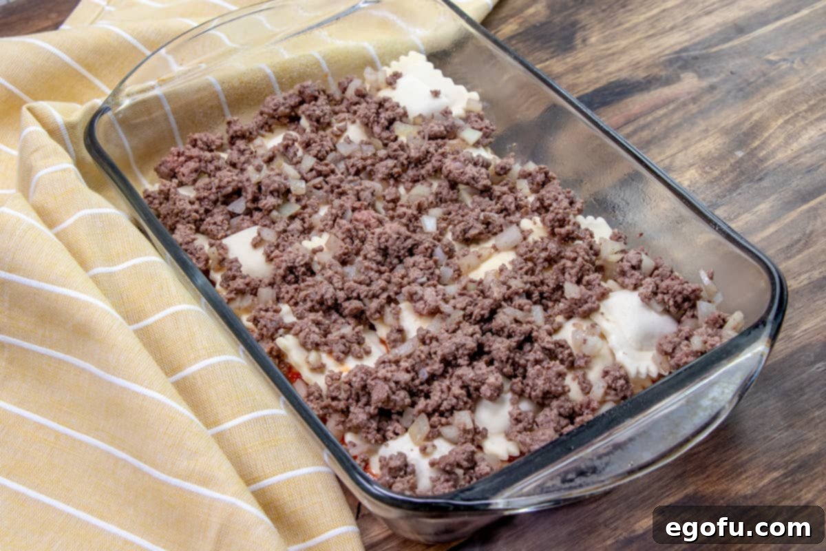 Ground beef and onion mixture added on top of the frozen ravioli in the baking dish.