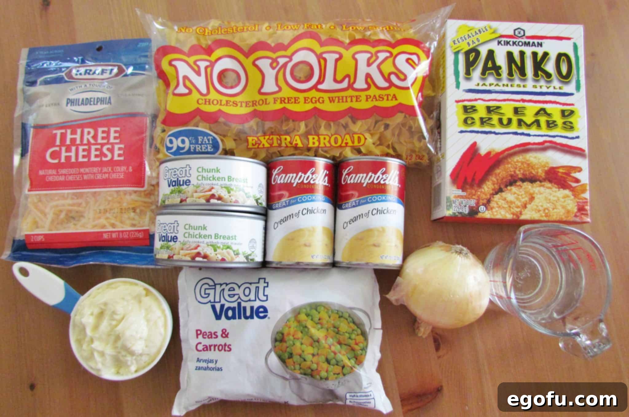 Ingredients for Easy Chicken Noodle Casserole including egg noodles, cheese, canned chicken, mayonnaise, peas and carrots, cream of chicken soup, and panko bread crumbs, neatly arranged for preparation.