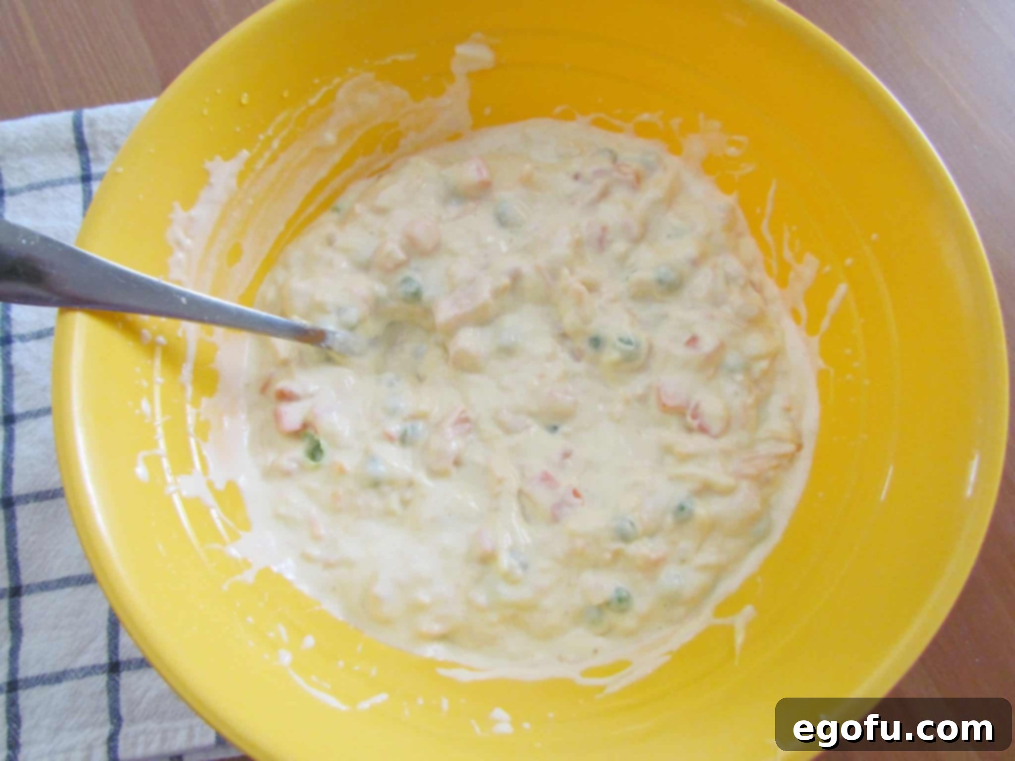 Chicken, cream of chicken soup, mayonnaise, peas and carrots, and other ingredients mixed together in a large bowl.