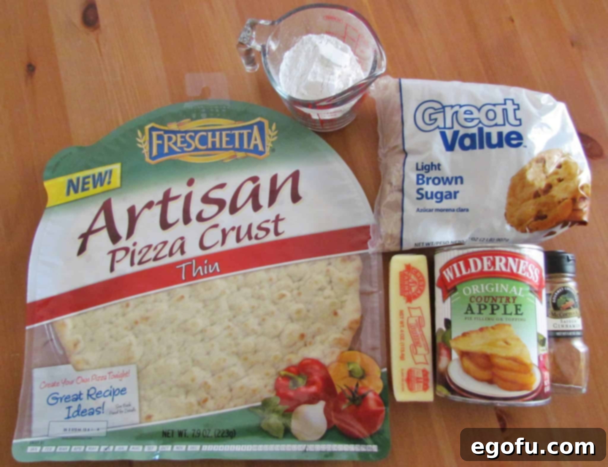 A visual spread of key ingredients for Apple Dessert Pizza: store-bought thin pizza crust, canned apple pie filling, softened salted butter, light brown sugar, all-purpose flour, and ground cinnamon, ready for preparation.