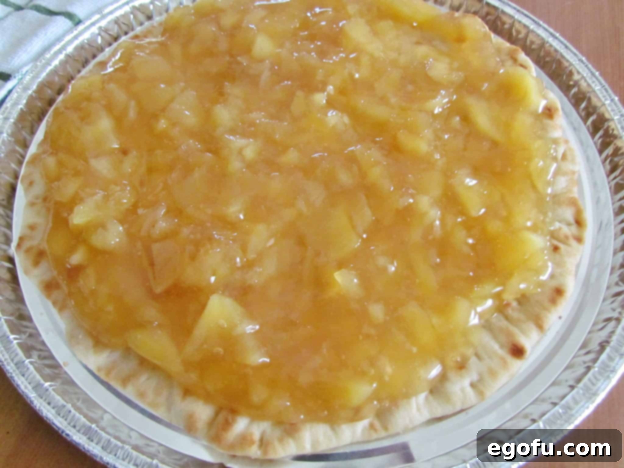 Evenly spread apple pie filling covers a store-bought thin crust pizza base, ready for the next layer of toppings.