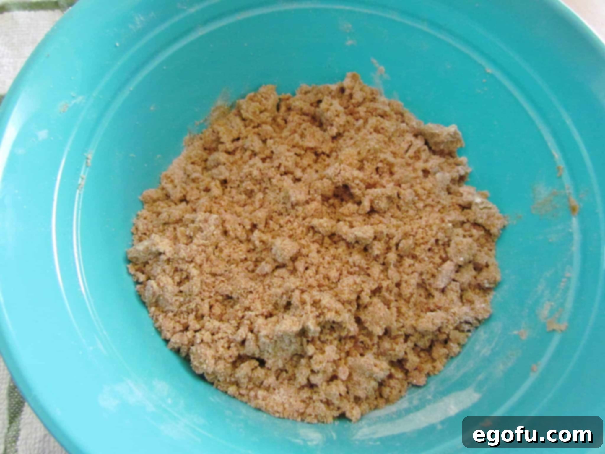 The fully mixed brown sugar crumble topping, showcasing its perfect coarse and crumbly texture in a blue bowl.