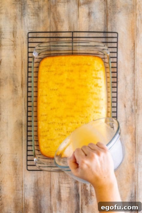 pouring cream of coconut over baked white cake.