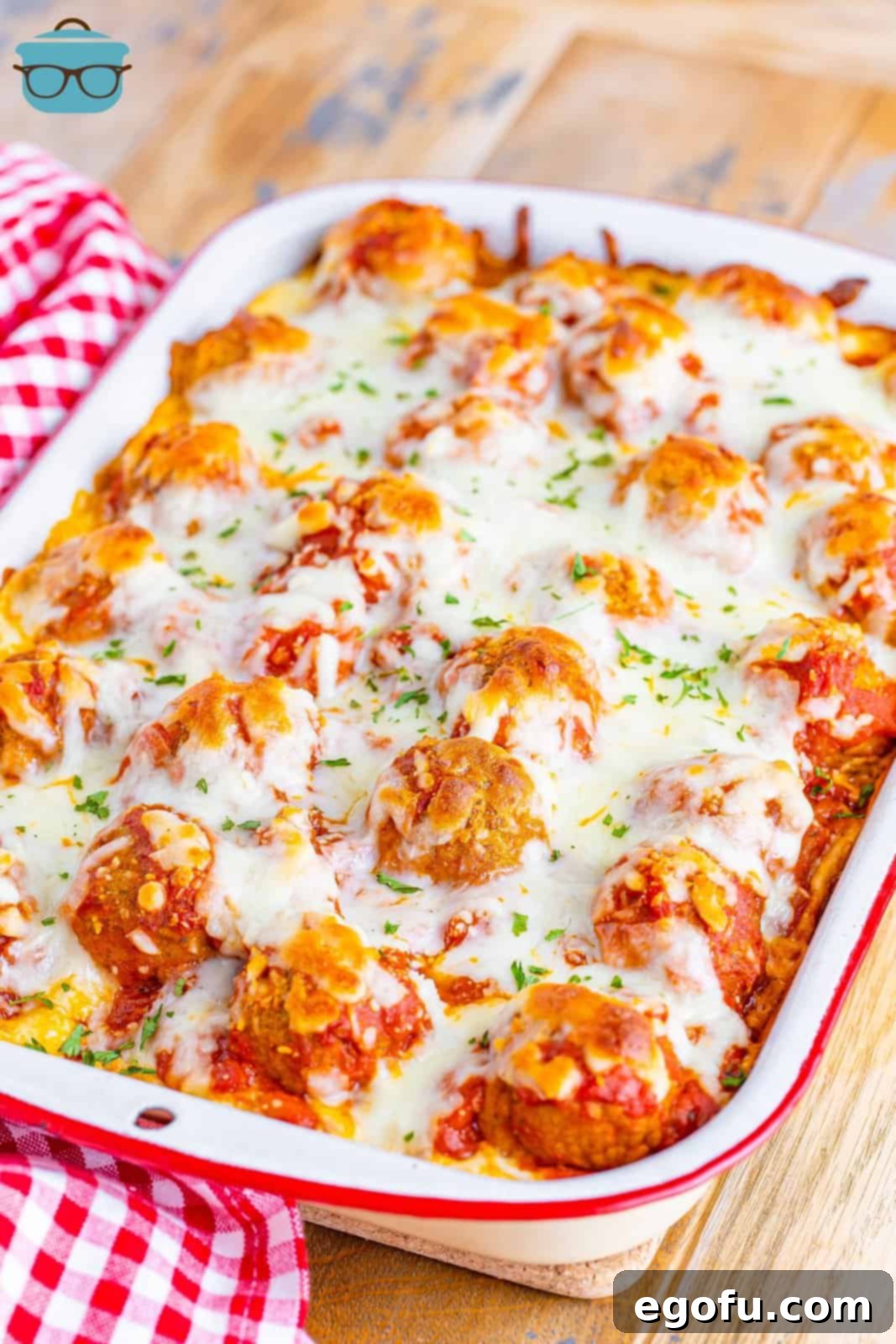 Angled photo of a fully cooked Meatball Sub Casserole, served in a white baking dish, showcasing melted cheese and savory meatballs.