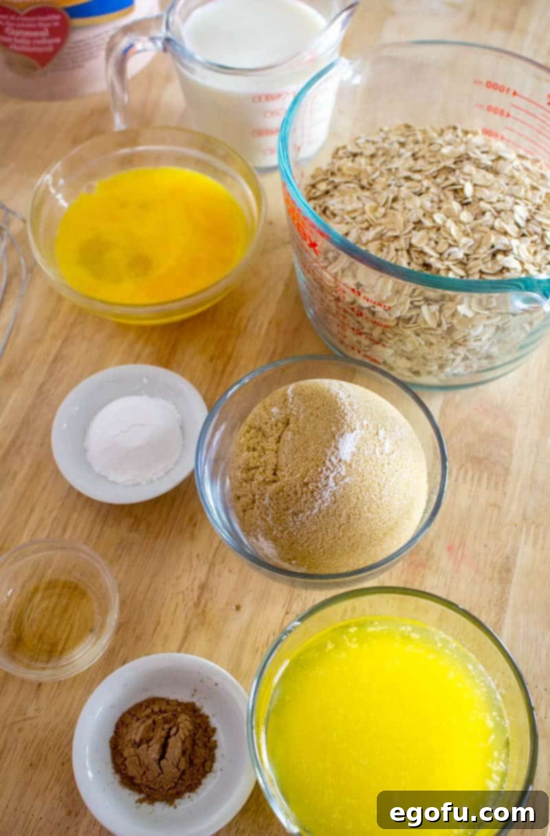 An array of key ingredients for Maple Brown Sugar Baked Oatmeal: quick-cooking oats, brown sugar, butter sticks, milk, eggs, baking powder, ground cinnamon, and a bottle of maple extract, all ready for mixing.