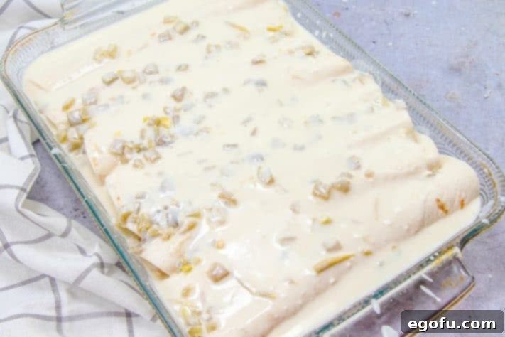 Decadent White Chicken Enchiladas 20 White cream sauce on top of rolled up enchiladas.