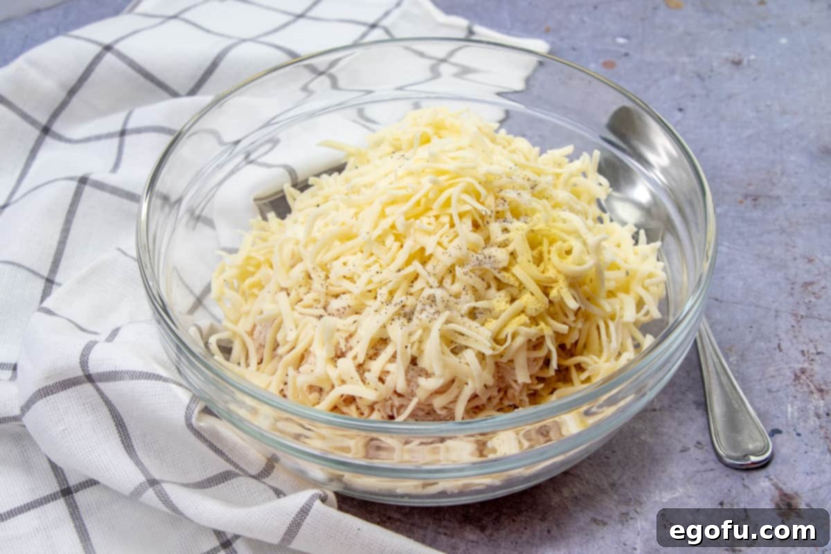 Decadent White Chicken Enchiladas 5 Shredded chicken, shredded cheese, salt, pepper, Adobo seasoning in a medium glass bowl