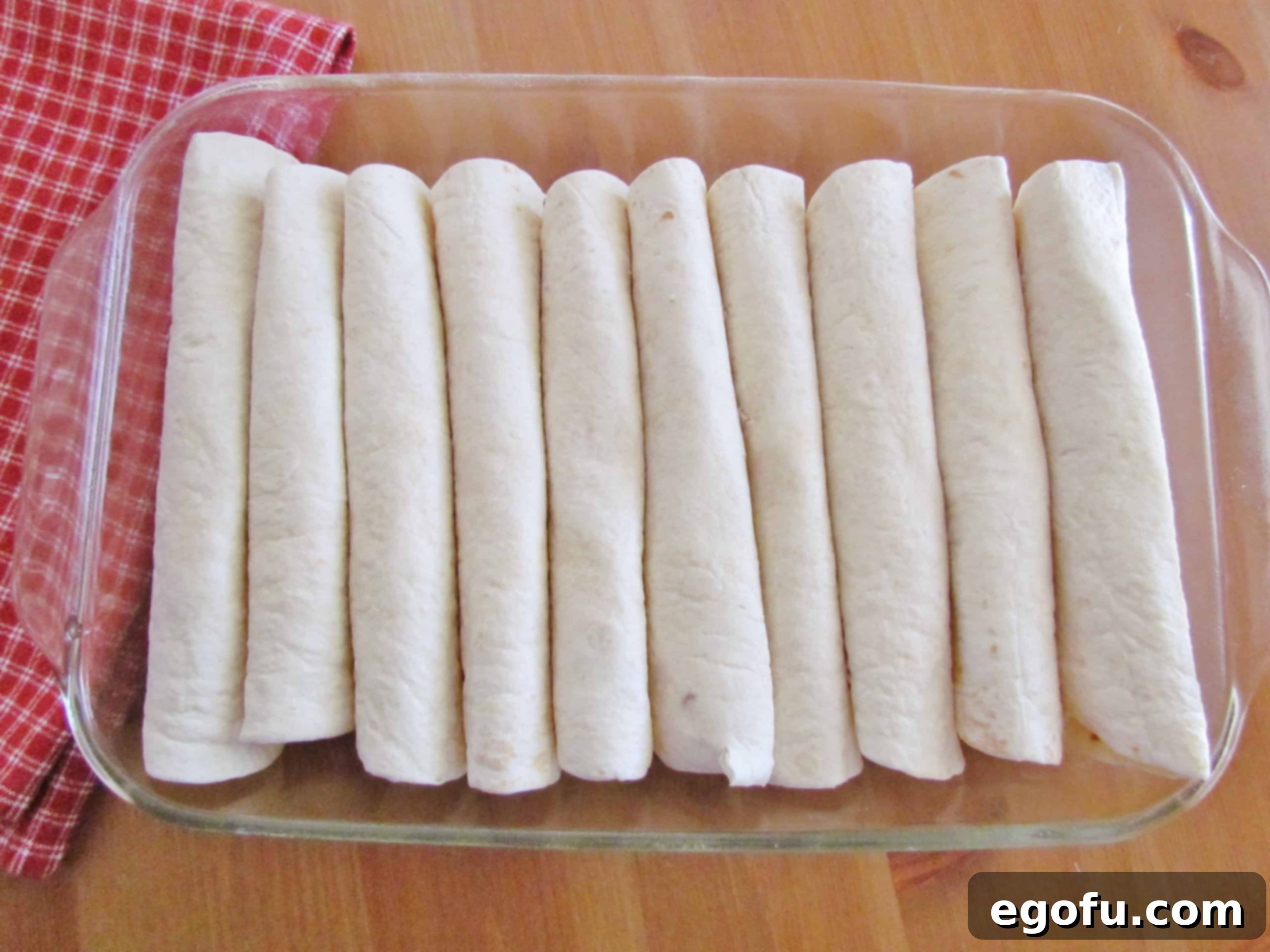 Decadent White Chicken Enchiladas 7 Flour tortillas filled with chicken in a baking dish.
