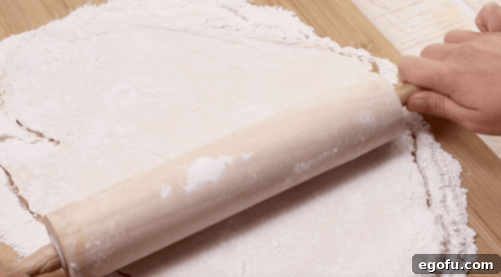 a wooden rolling pin rolling dumpling dough into a flat shit