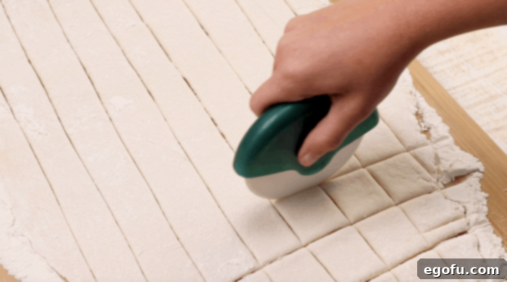 rolling flat dumpling dough with a pizza cutter to cut squares