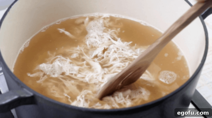 shredded chicken added to chicken broth in a large stock pot