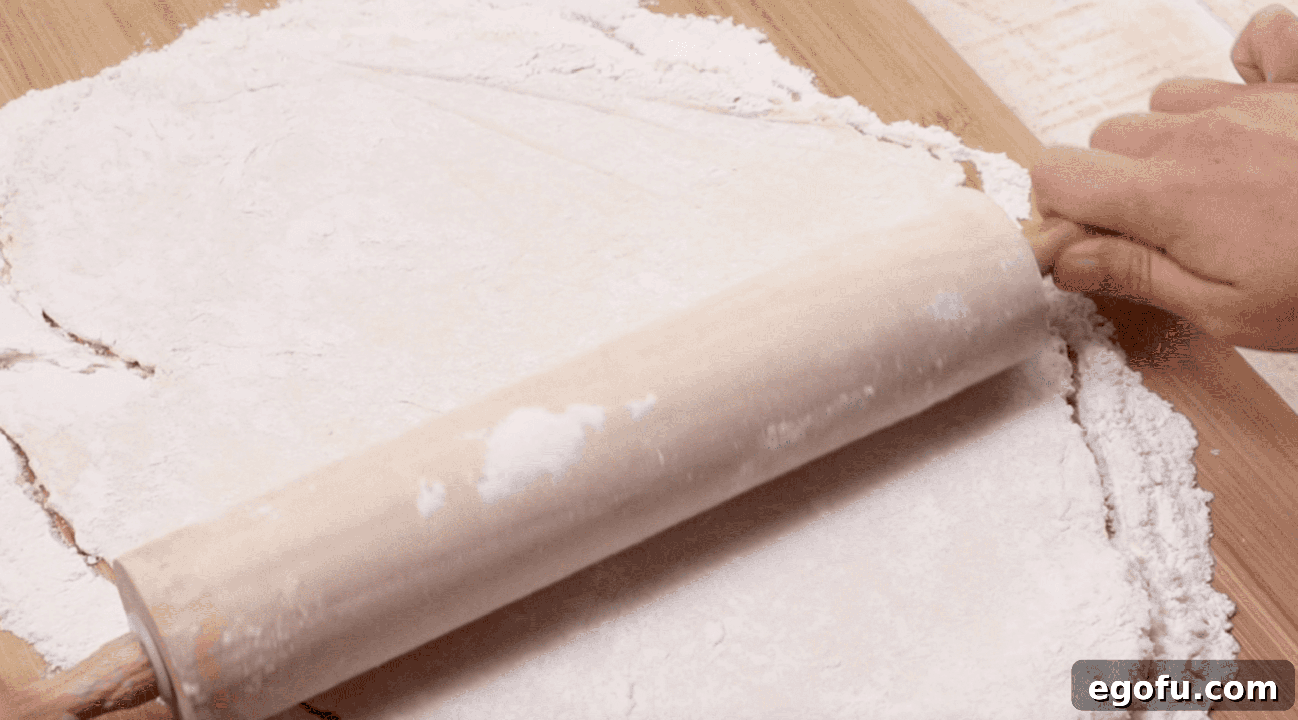 a wooden rolling pin rolling dumpling dough into a flat shit