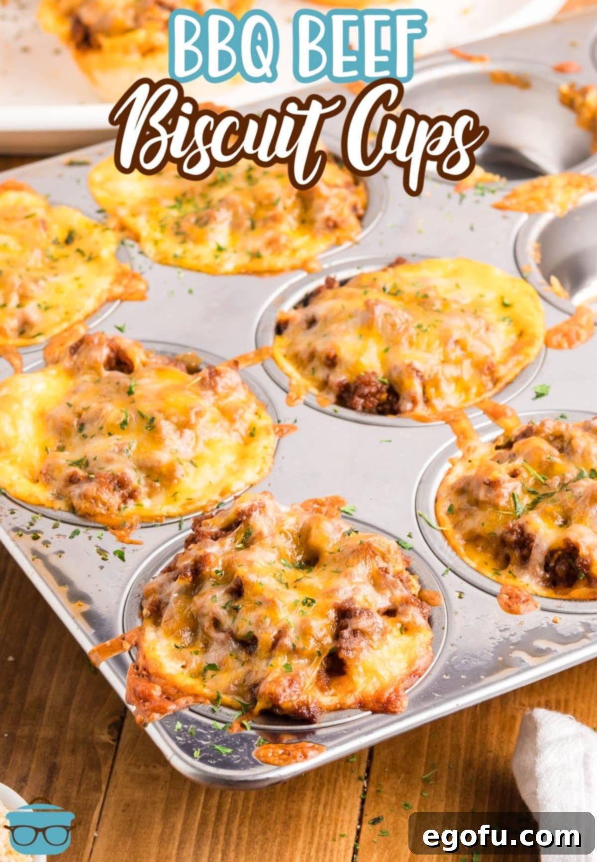Smoky Beef Biscuit Pockets 4 A close-up of a muffin tin filled with perfectly baked BBQ Beef Biscuit Cups, showing the golden biscuits and melted, bubbly cheddar cheese.