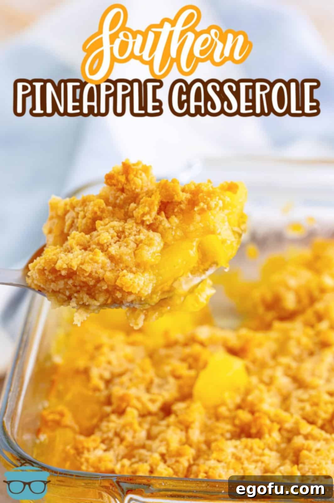 A large silver spoon carefully scooping a generous portion of warm, gooey pineapple casserole from its baking dish, ready to be served.
