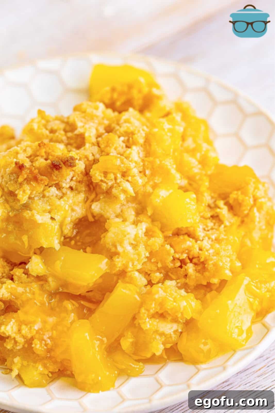 A single serving of warm pineapple casserole presented on a small, round white plate, ready to be savored.