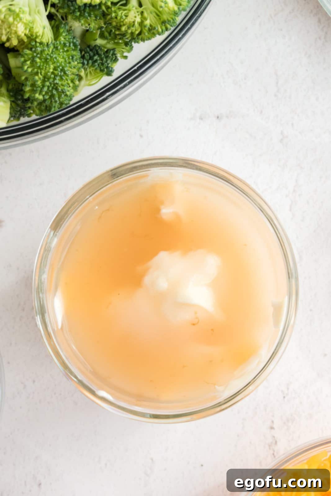 A bowl of mayonnaise, sugar, and vinegar being whisked together to form the creamy dressing.