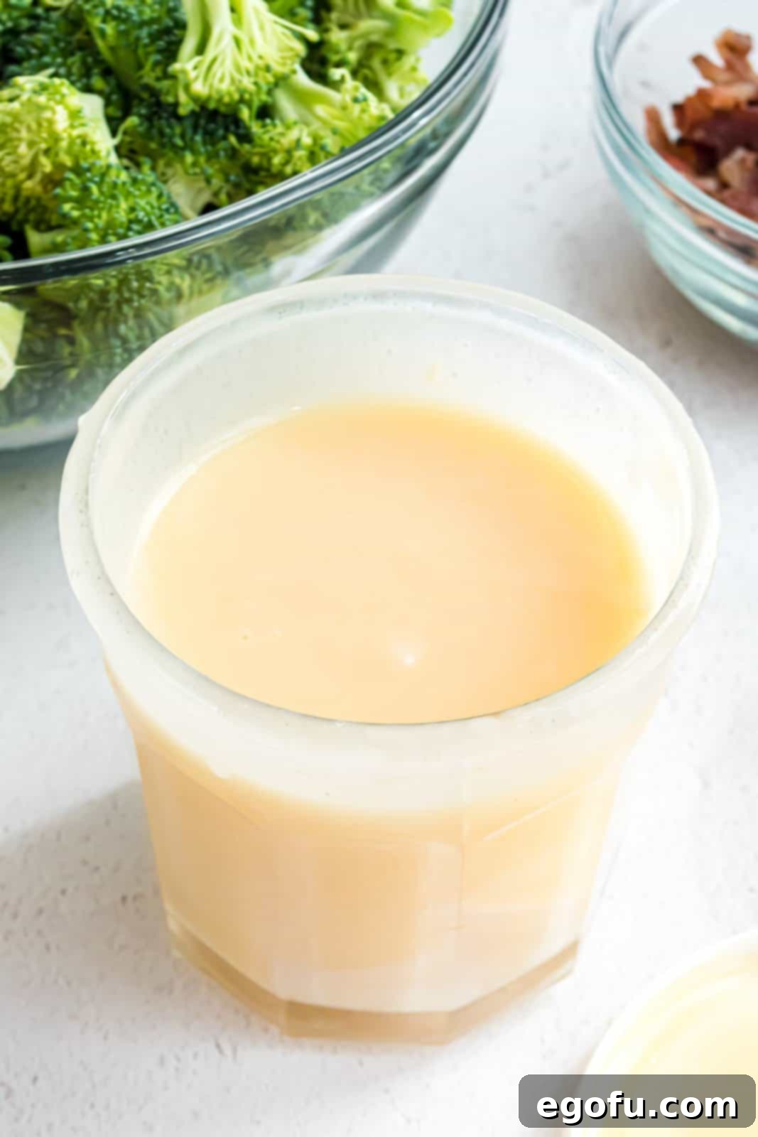 A mason jar with dressing ingredients being vigorously shaken to combine them.