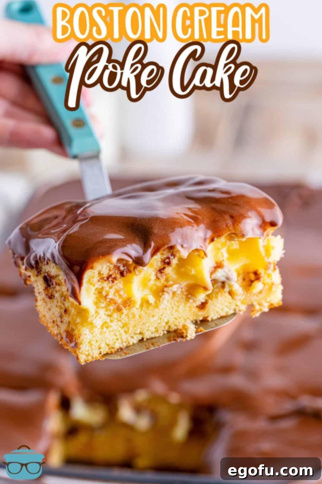 A close-up shot capturing a spatula carefully lifting a perfectly formed slice of Boston Cream Poke Cake from a baking pan, clearly showcasing the distinct layers of moist yellow cake, creamy vanilla pudding absorbed within, and the smooth, glistening chocolate frosting on top.