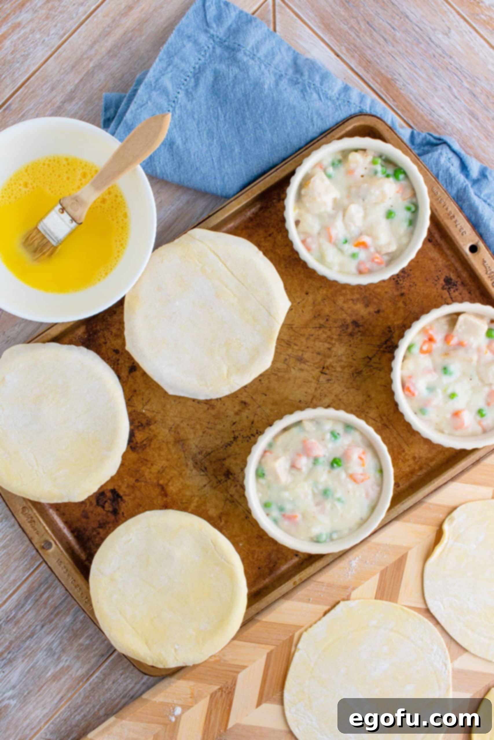 Three of the six filled ramekins, now topped with puff pastry circles, showing the edges sealed to the bowls.