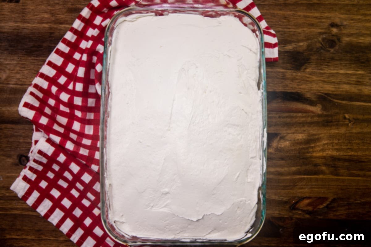 sweetened cream cheese mixture spread evenly onto cooled white cake in baking dish.
