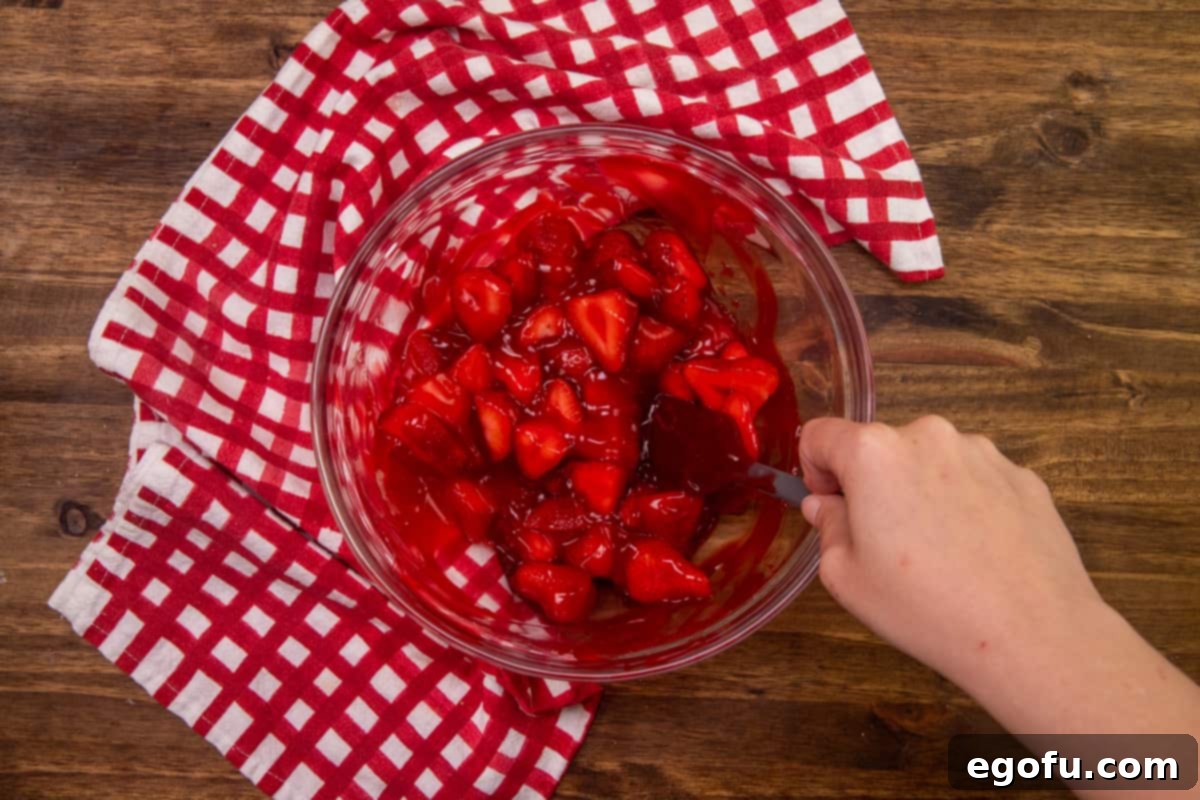 sliced strawberries and strawberry glaze mixed together in a clear bowl.