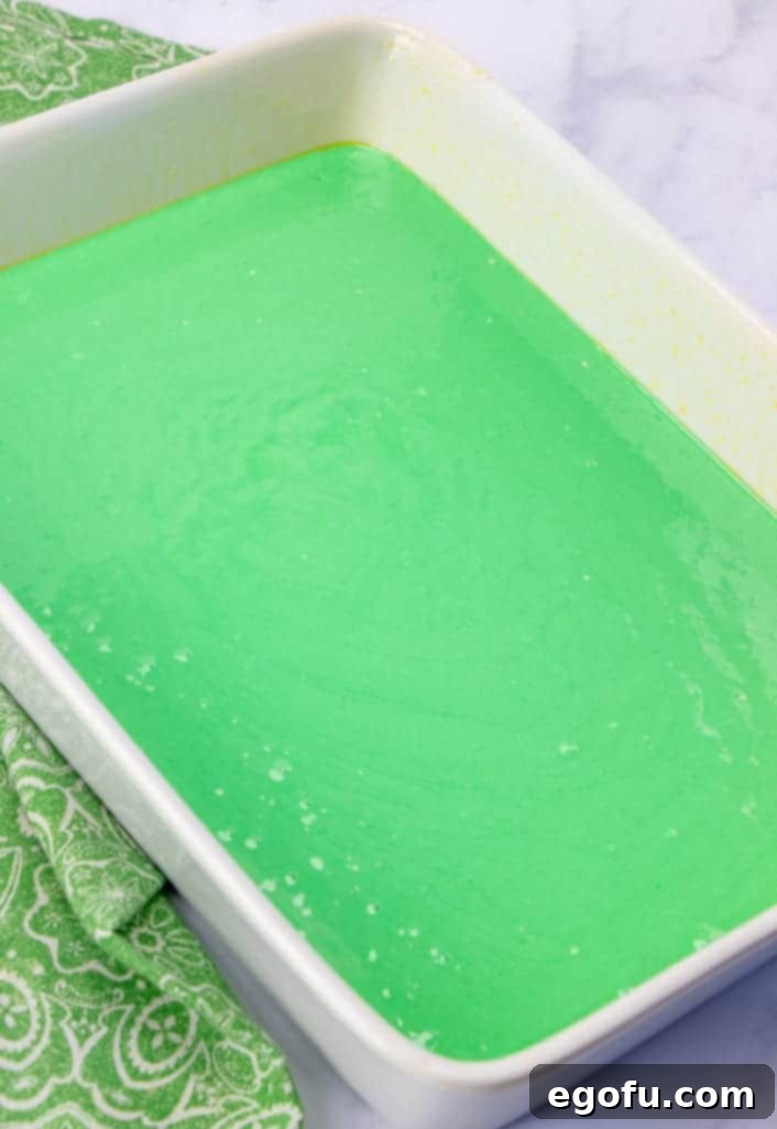 Effortless Grasshopper Indulgence 7 The vibrant green cake batter smoothly poured into a greased white 9x13 inch baking pan, ready for the oven.
