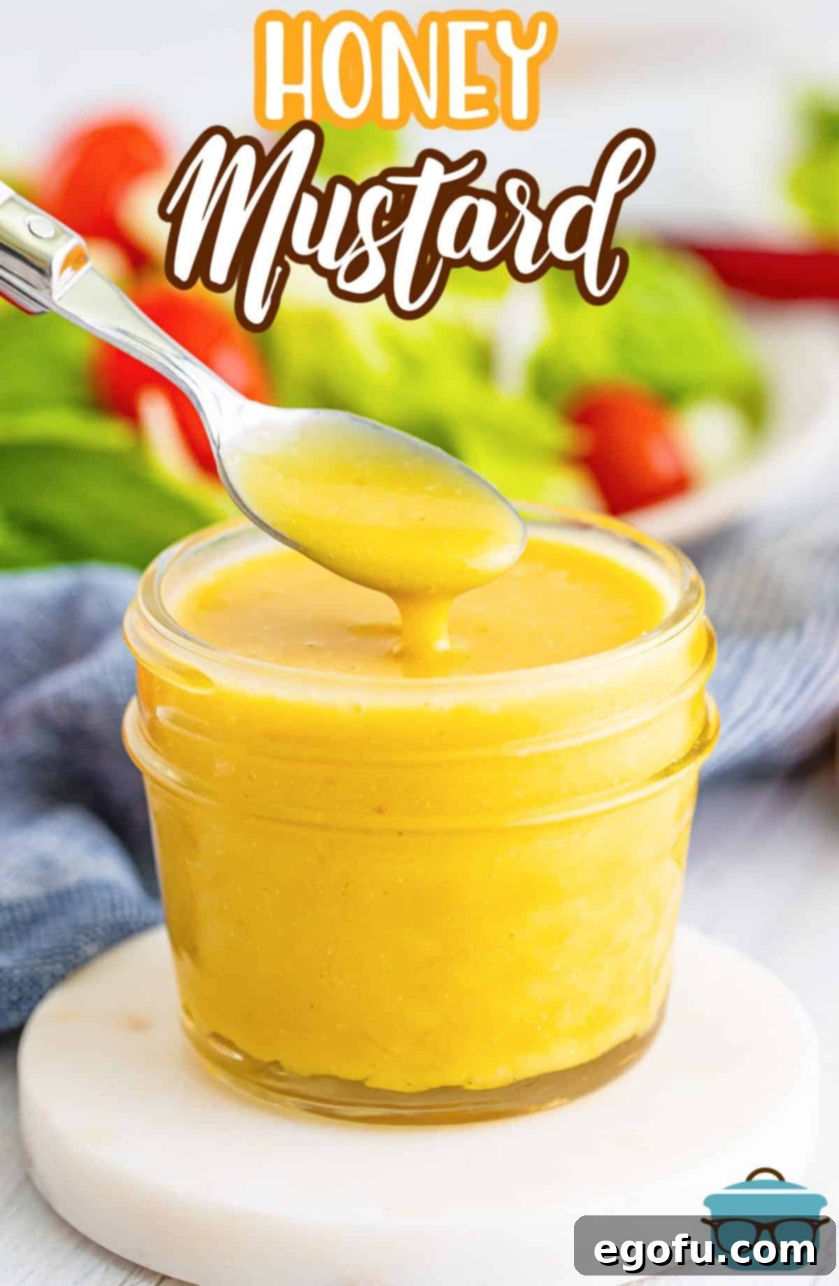 A spoon dripping some Homemade Honey Mustard back into the jar.