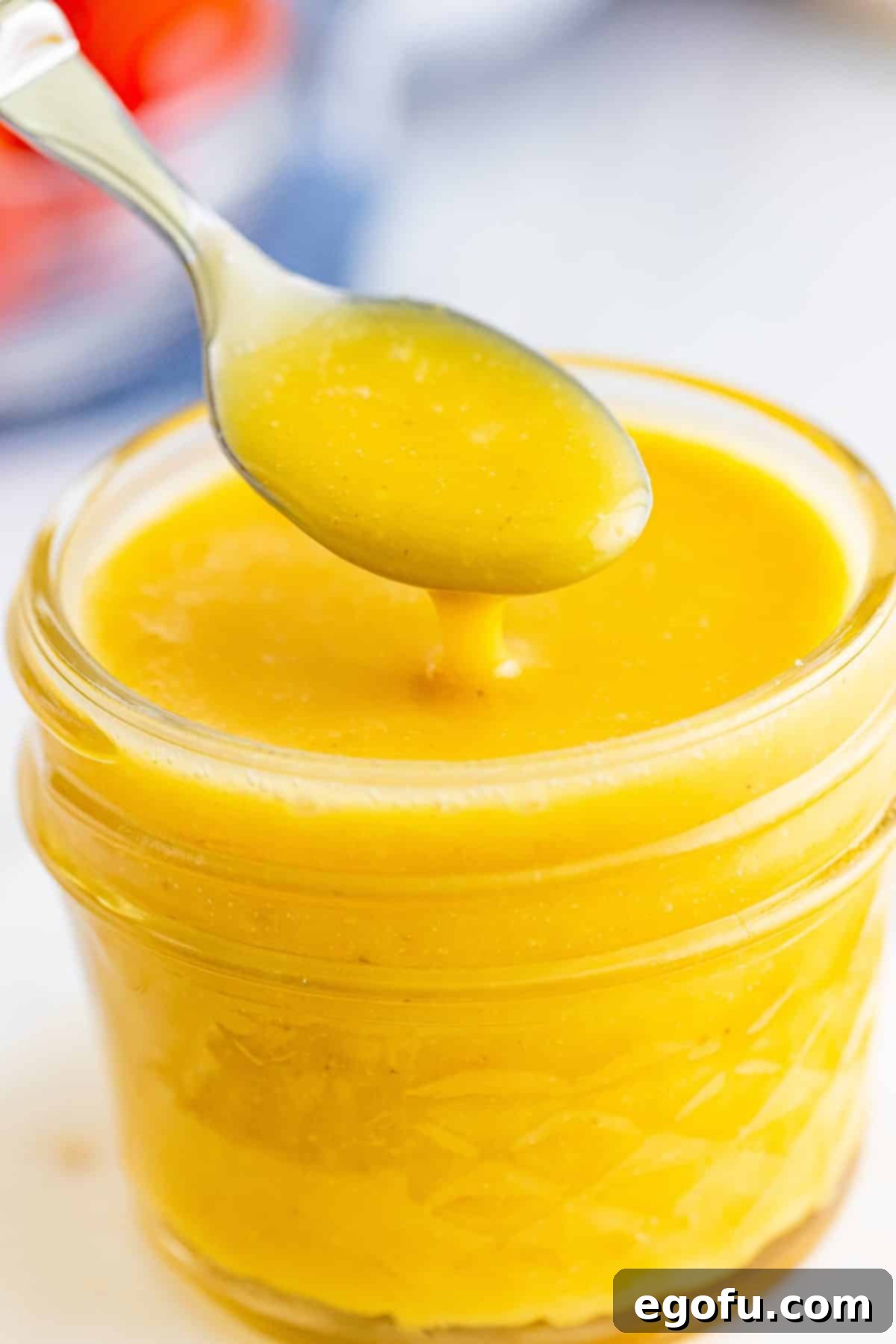 A jar of Homemade Honey Mustard with a spoon in it.