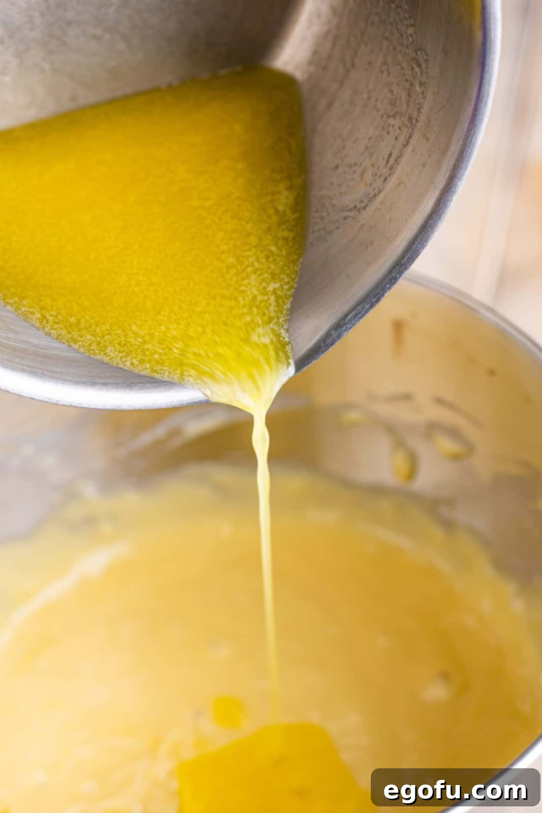 Swirl of Spice Cake 6 Melted butter is slowly being added to the swirling cake batter in a mixing bowl, creating a smooth and rich consistency.