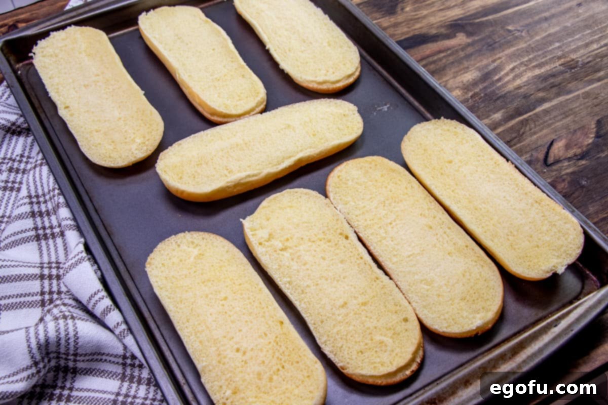 sub roll buns opened and on a baking sheet.