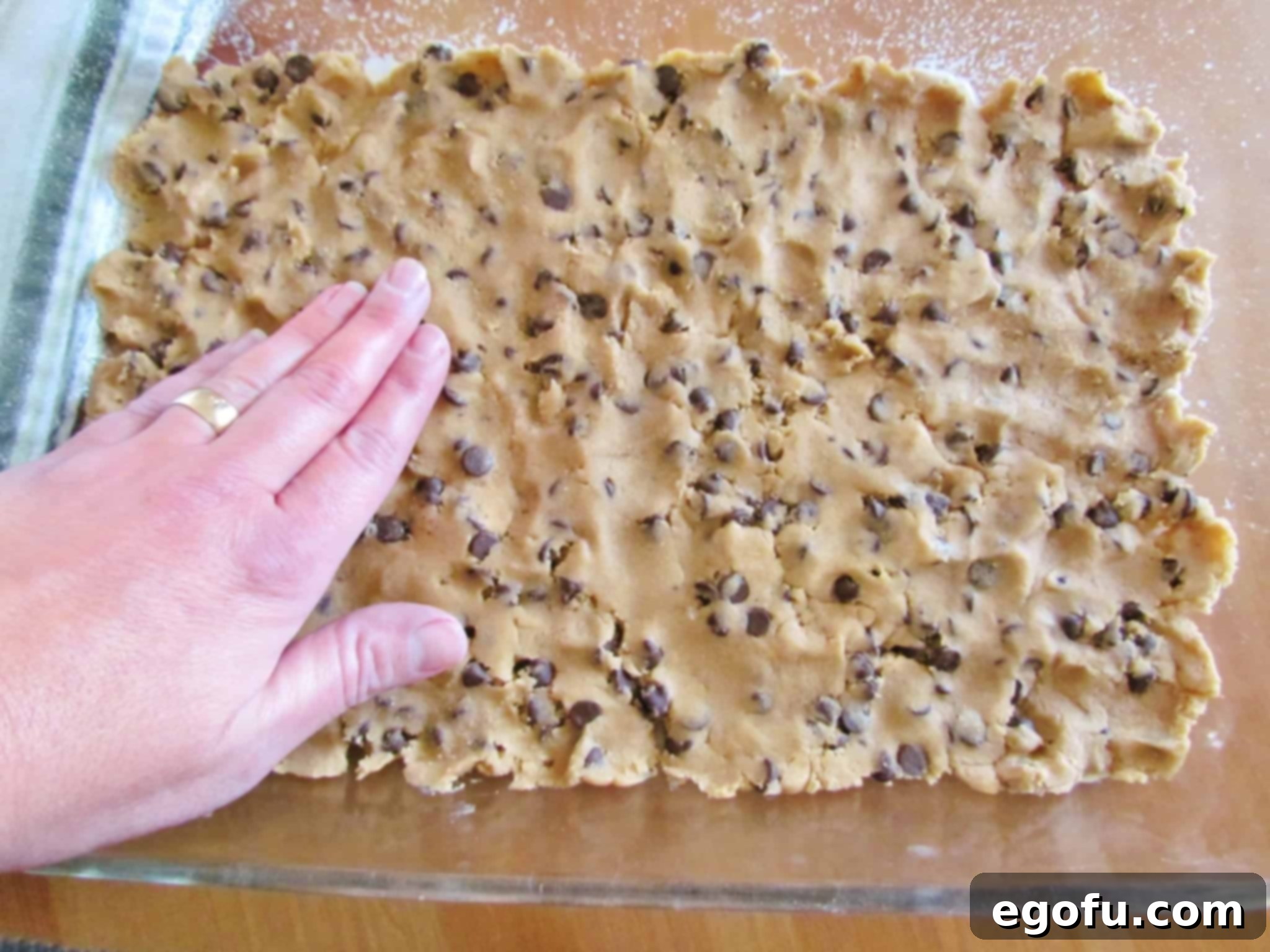 C Is For Cookie Layers 5 chocolate chip cookie dough spread into a glass Pyrex 9x13 baking dish.