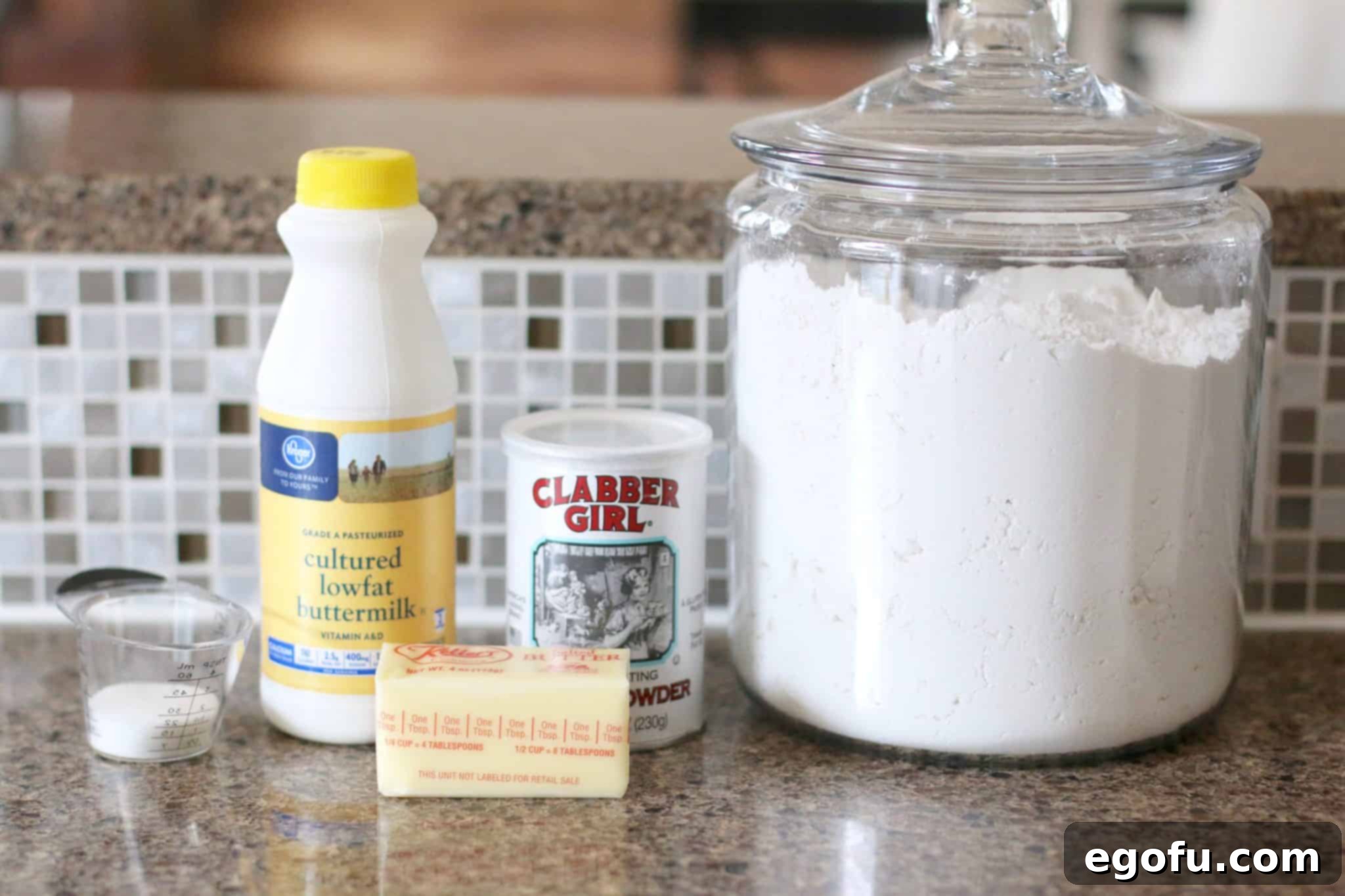 Golden Butter Biscuits 5 Ingredients needed to make butter dip biscuits: All-Purpose Flour, Buttermilk, Salted Butter, Baking Powder arranged on a wooden surface.